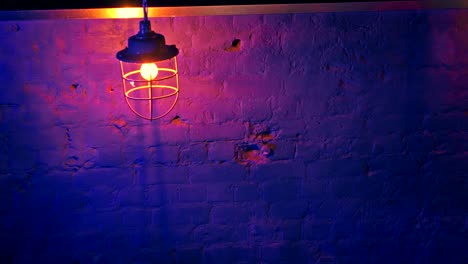 linterna de loft de hierro de estilo antiguo con bombilla eléctrica amarilla contra la pared de ladrillo azul