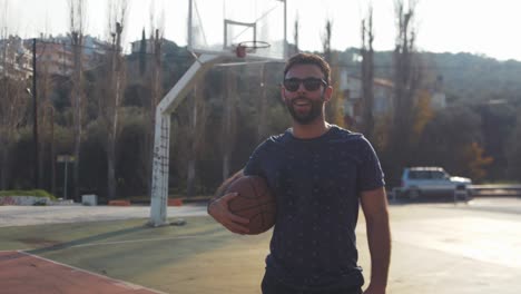 male basketball player stands with ball under arm after training handheld video portrait