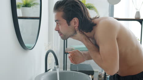 hombre lavándose la cara en el baño