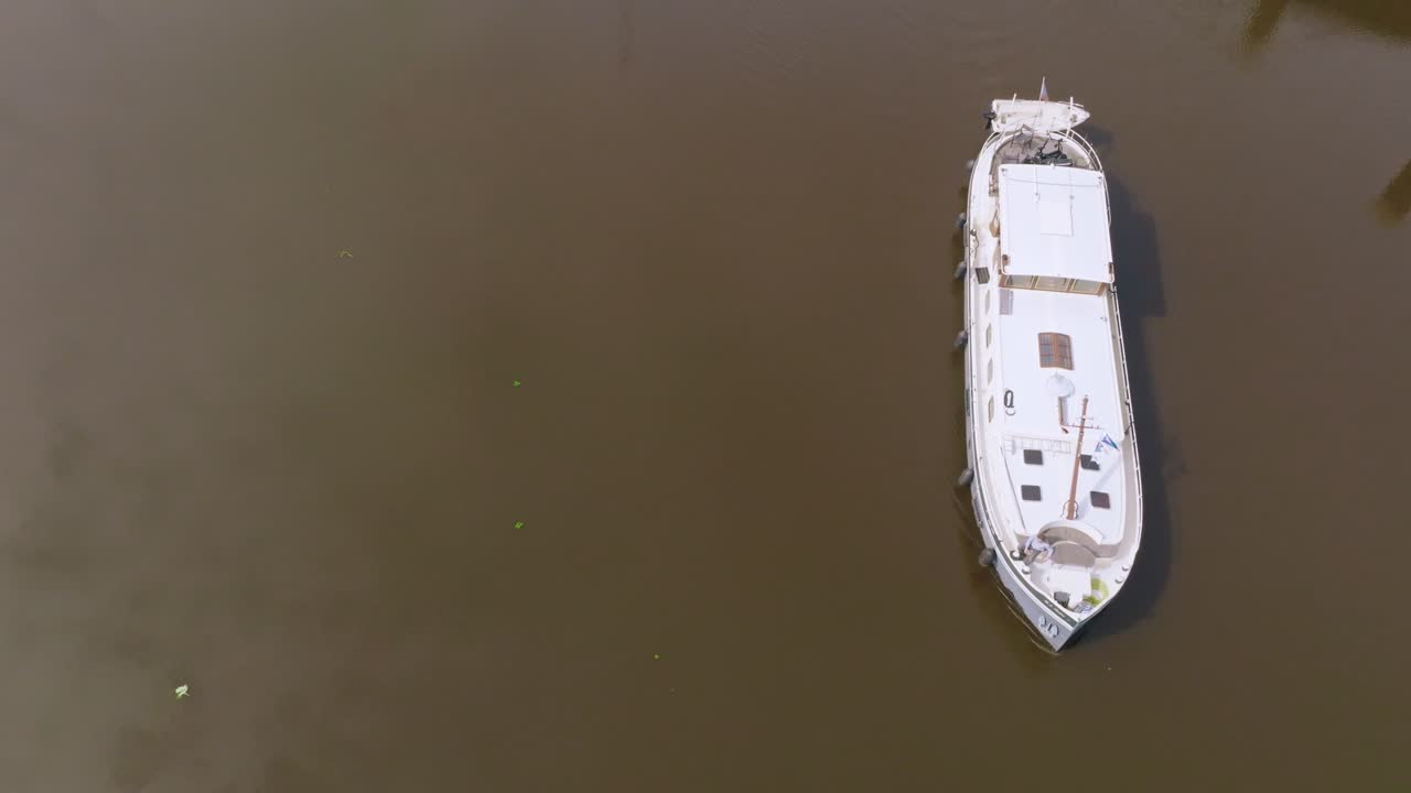 Tilt up capturing a white boat arriving at the canal lock in a rural zone under a cloudy sky with natural light.