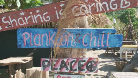 static shot of wooden signs on the beach at a beach bar that is closed due to the pandemic in thailand