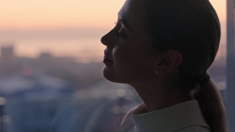 Hermosa-Mujer-De-Negocios-Mirando-Por-La-Ventana-Contemplando-Un-Estilo-De-Vida-Exitoso-Planificando-Con-Anticipación-Disfrutando-De-La-Vista-De-La-Ciudad-Desde-El-ático-Al-Atardecer