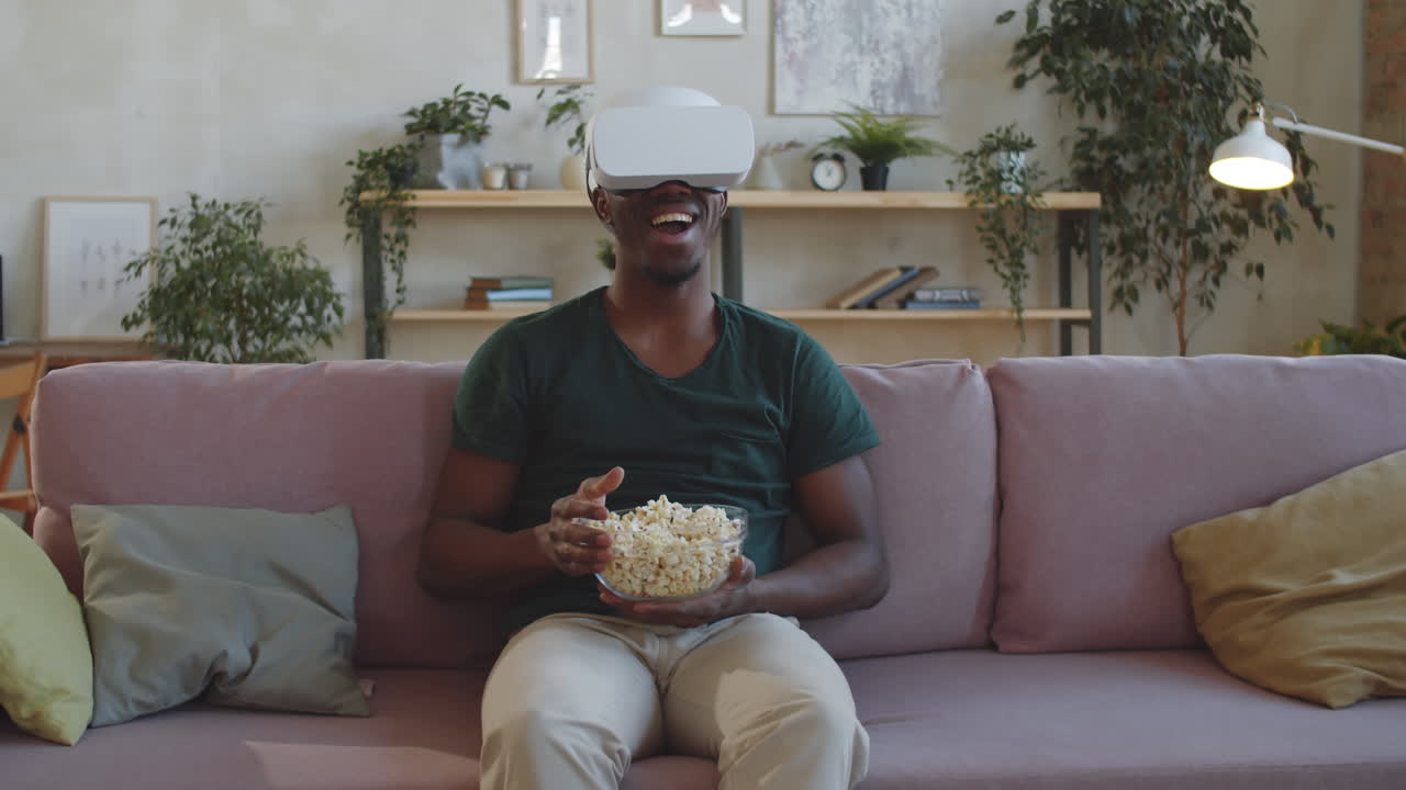 hombre negro comiendo palomitas de maíz y viendo una película en auriculares vr