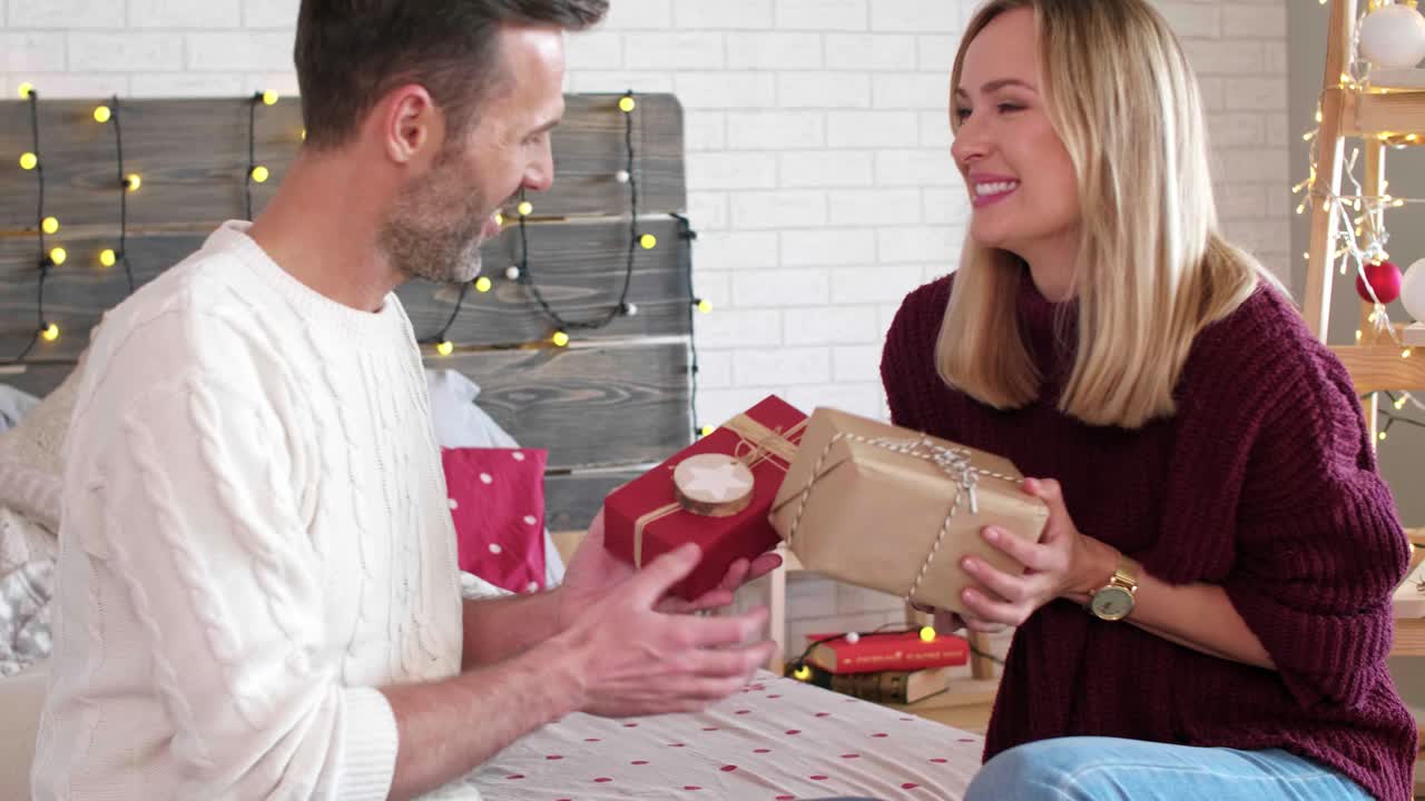 una pareja enamorada intercambiando regalos de navidad entre sí.