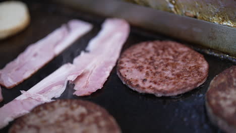 preparing burgers and bacon on a griddle