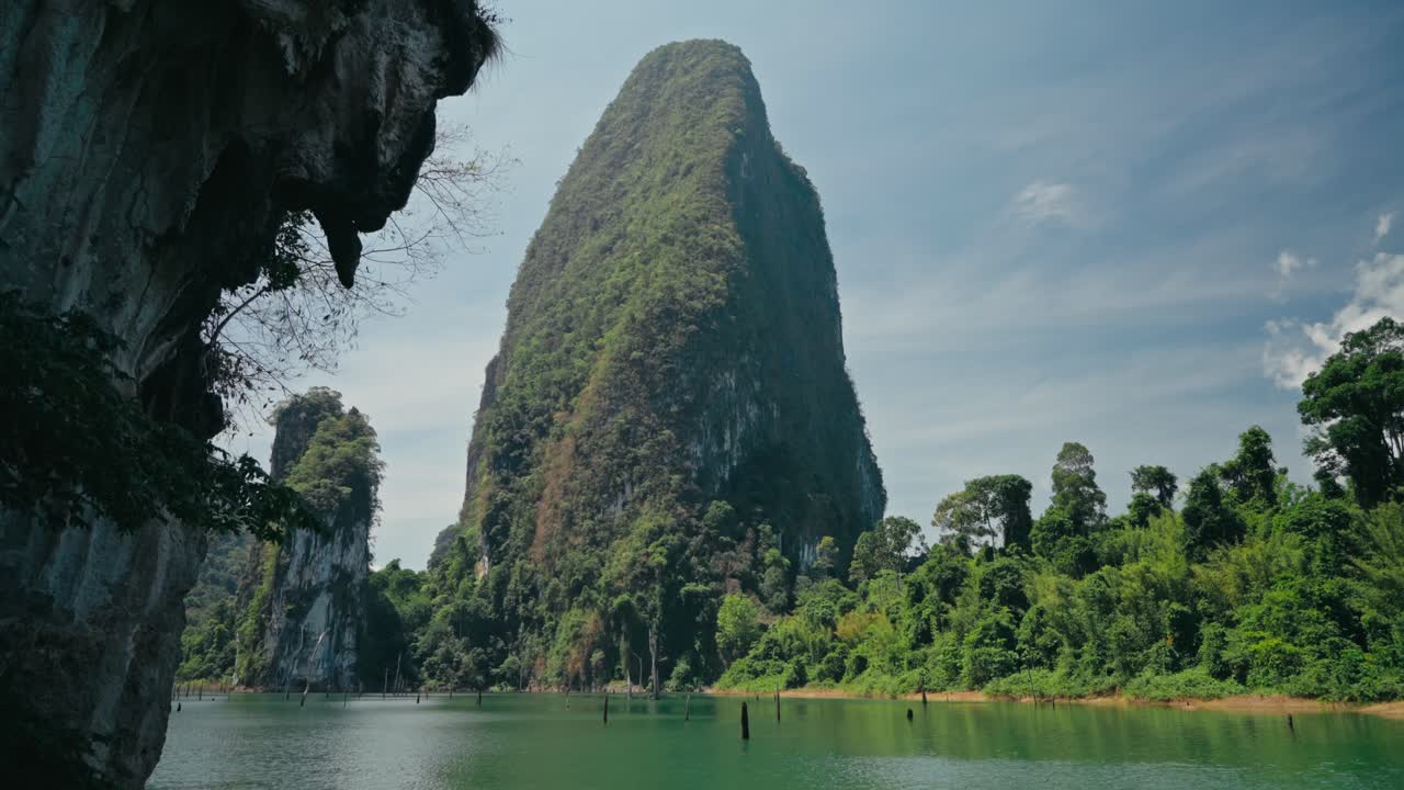 Impresionante acantilado de piedra caliza se eleva sobre agua turquesa en el Parque Nacional Khao Sok, Tailandia. Paisaje tropical impresionante con colores vivos y serena belleza natural.
