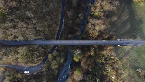 Top-view-of-an-empty-bridge-in-a-forest-going-over-a-rocky-river-bank-with-clear-blue-water-in-a-early-spring-day