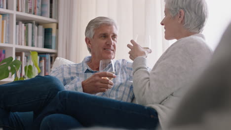 Feliz-Pareja-De-Ancianos-Bebiendo-Vino-Relajándose-En-El-Sofá-De-Casa-Haciendo-Tostadas-Celebrando-El-Aniversario-Disfrutando-De-Una-Relación-Romántica-En-Un-Cómodo-Retiro-4k