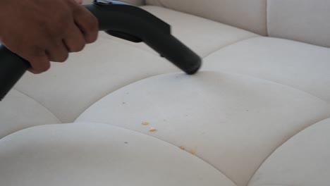 a person is vacuuming a couch with a hand-held vacuum cleaner.