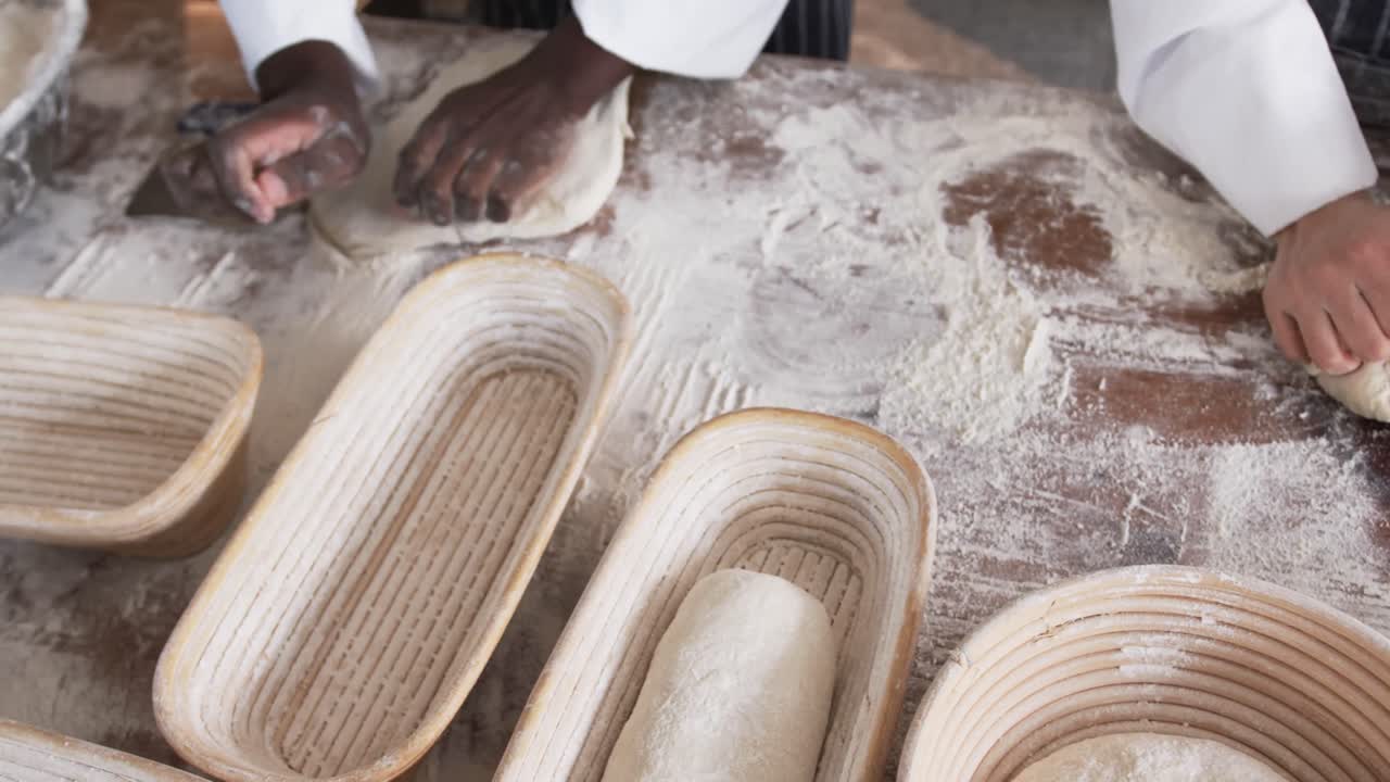 Padeiros diversos trabalhando na cozinha da padaria, sovando a massa em câmera lenta.
