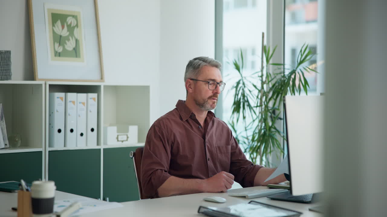 Fokuseret forretningsmand arbejder på computer og dokumenter på et moderne kontor