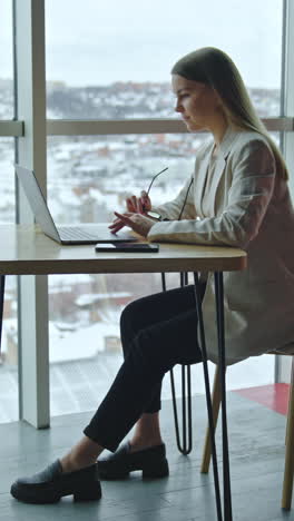 attractive lifestyle girl in modern office. cheerful young businesswoman working with laptop. vertical video