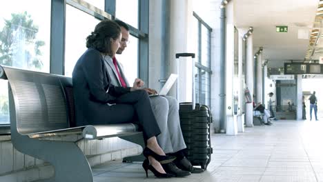 Business-colleagues-using-laptop-at-railway-station