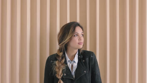 Lindo-Retrato-De-Mujer-Hispana-De-Una-Hermosa-Joven-Que-Parece-Pensativa-Contemplativa-Ante-La-Cámara-En-Un-Fondo-De-Madera-Con-Chaqueta-De-Cuero