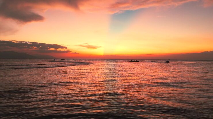 Colorful tropical sunset over calm sea with boats in Philippines