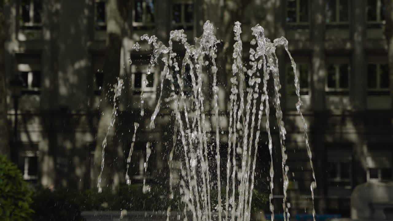 Water splashing in fountain against city background in Madrid, slow motion view