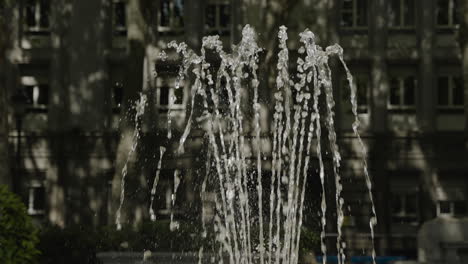 Agua-Salpicada-En-Una-Fuente-Contra-El-Fondo-De-La-Ciudad-En-Madrid,-Vista-En-Cámara-Lenta