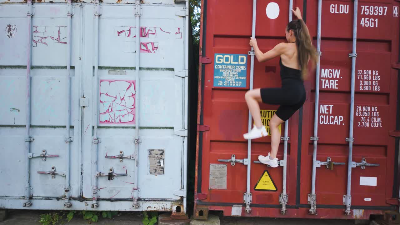 Athletic girl climbing up a container to escape. Static at day time