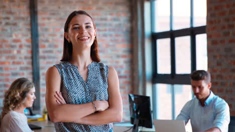 retrato de una joven mujer de negocios sonriente en una oficina ocupada con colegas trabajando en el fondo