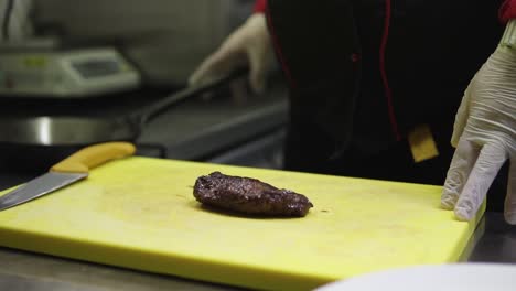 Chef-cutting-beef-steak-in-the-kitchen-on-yellow-chopping-board-|-SLOWMOTION