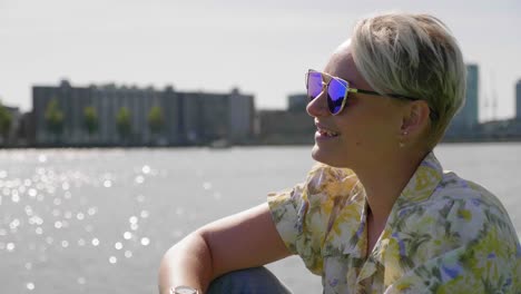 una joven elegante se relaja bajo el sol de verano, sentada en un muelle