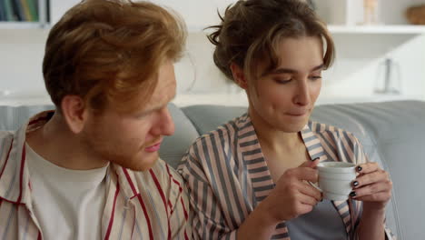 Closeup-love-couple-drinking-coffee-at-home.-Young-family-hugging-on-couch.