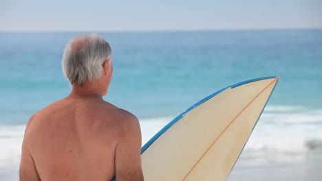 Anciano-Mirando-El-Océano-Con-Una-Tabla-De-Surf