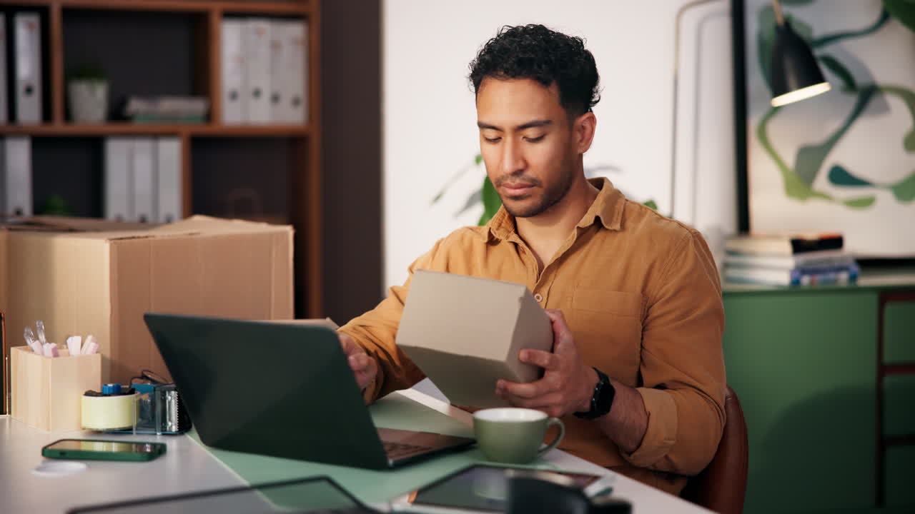 Man working on laptop with boxes in office