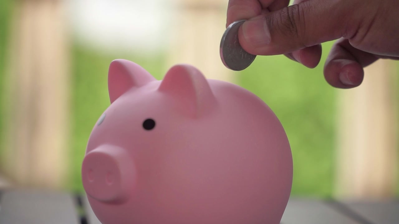 Close-up of piggy bank inserted by coins, saving money for future investment and financial stability.