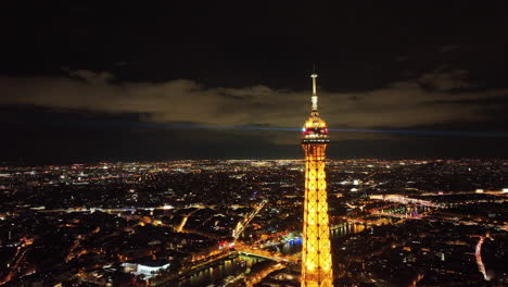 Eiffelturmgipfel-Bei-Nacht-Mit-Funkelnden-Lichtstrahlen,-Blick-Auf-Die-Stadt,-Paris