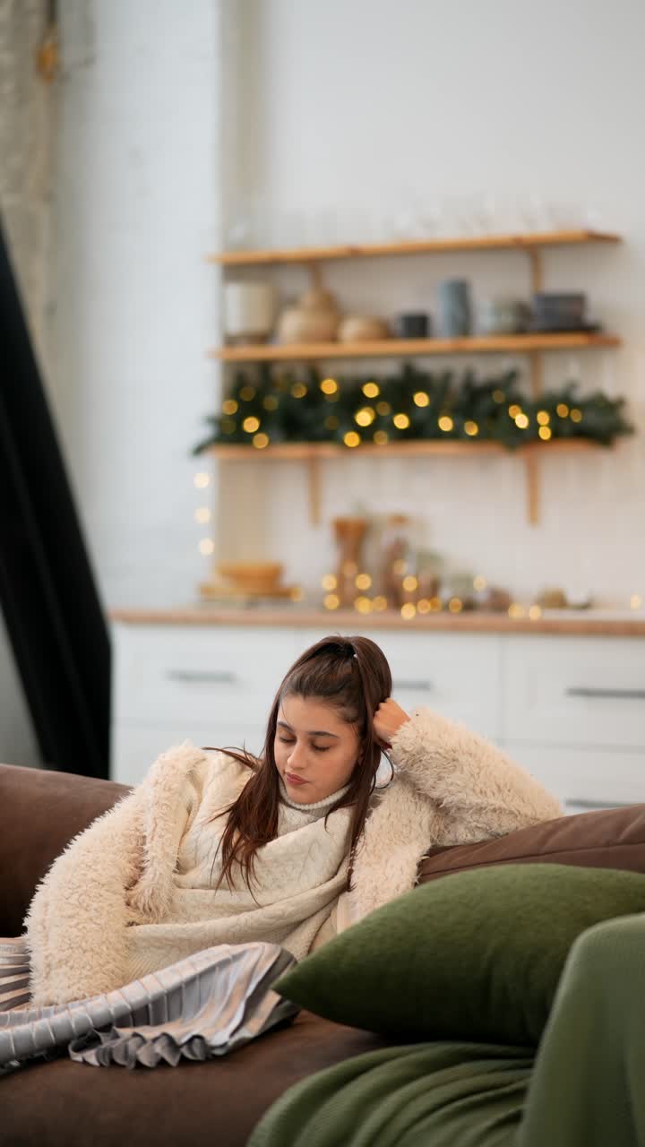 십대 소녀가 크리스마스 동안 편안한 소파에서 휴식을 취하고 있습니다.