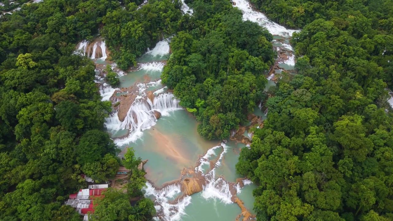 Una sorprendente prospettiva aerea con drone dall'alto che rivela i sinuosi livelli del fiume turchese e la lussureggiante volta della foresta pluviale delle Cascate di Agua Azul nel Chiapas, Messico.