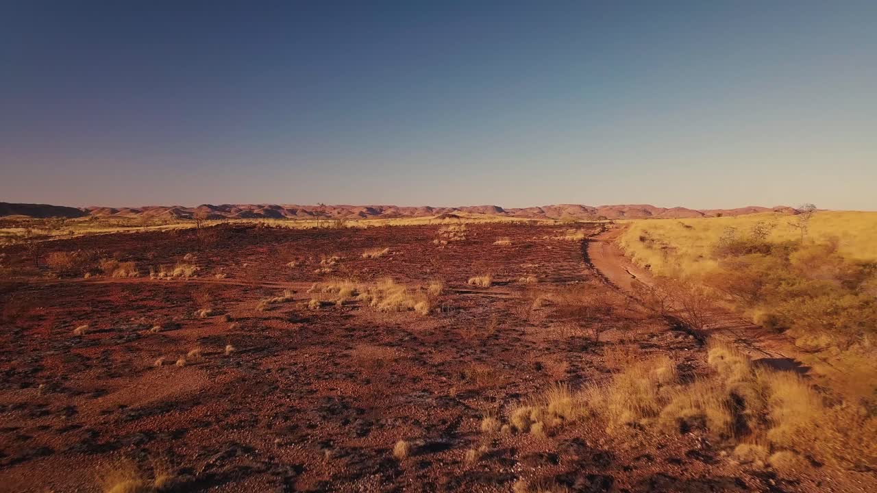 Orman yangını sonrası Avustralya Çölü'nde çakıllı yolda alçaktan drone ile 4x4 kamyoneti takip