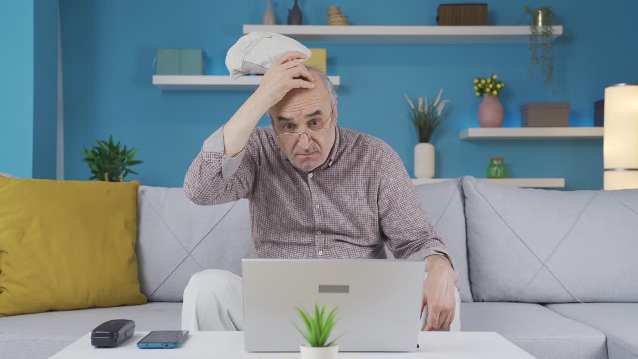 The old man looking at the laptop is confused and unhappy.