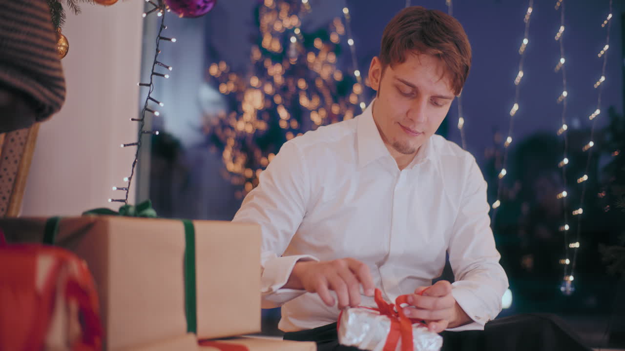 남자가 집에서 편지를 읽은 후 크리스마스 선물을 열고