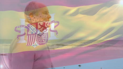 animation of flag of spain over happy senior caucasian man on beach