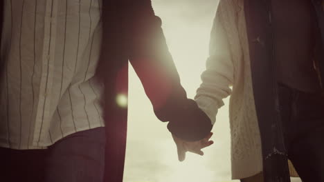 Young-couple-holding-hands-on-sunset-sky-nature-background.-Love-calm-concept.