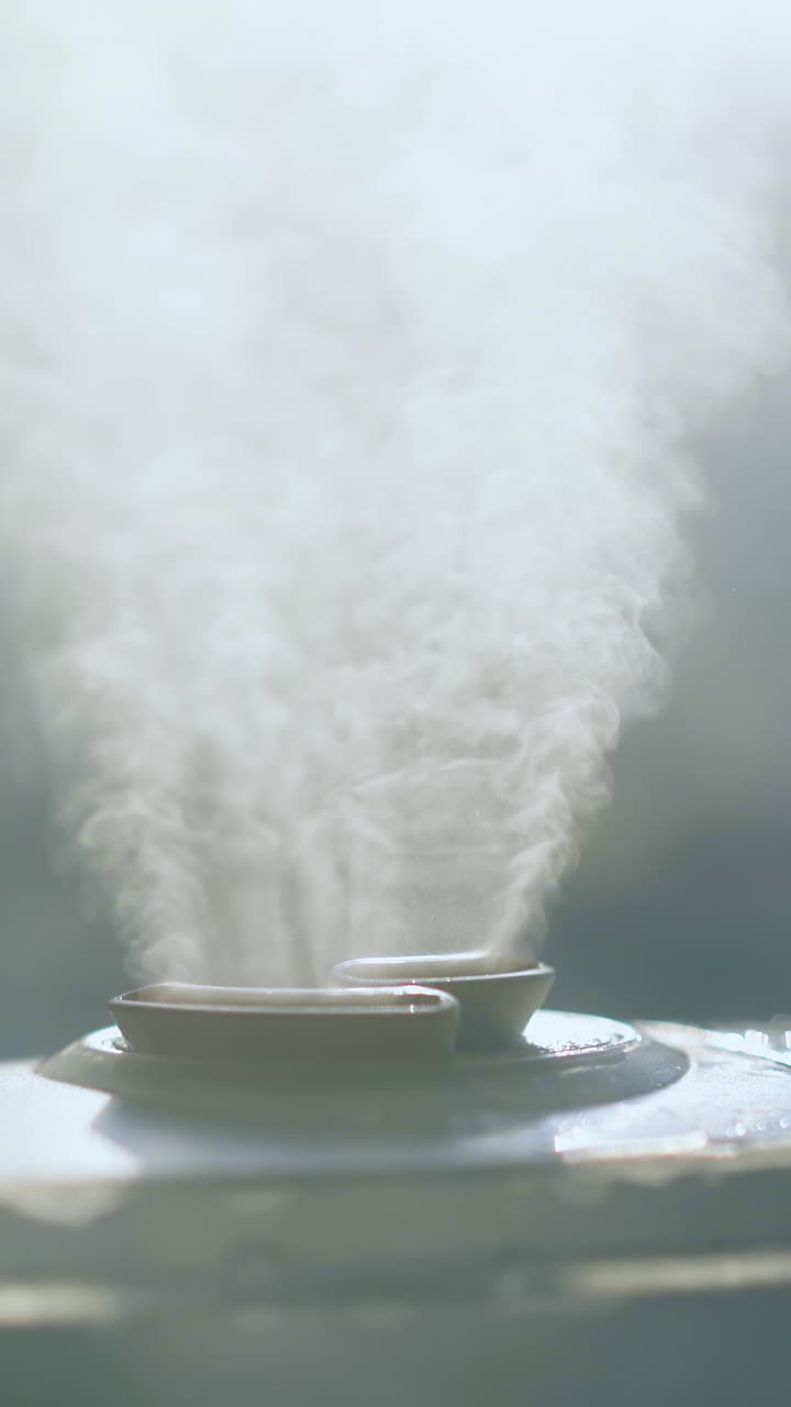 CU shot: air ionizer emits steam cloud to humidify atmosphere to clean and neutralize bacteria in room extreme close view