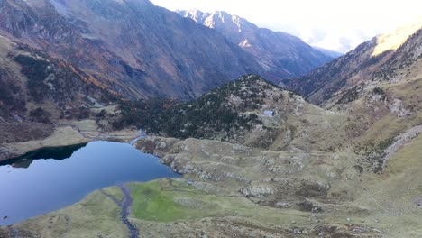 Lac-d'Espingo-lake-between-snowy-peaks-located-in-Haute-Garonne,-Pyrénées,-France,-Aerial-orbit-shot