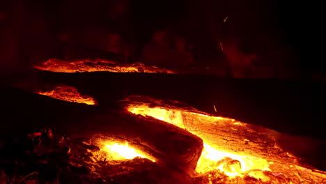 4k-Nahaufnahme-Lagerfeuer,-Das-Mit-Brennender-Glut-Und-Rauch-Durch-Baumstamm-Brennt