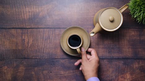 hand holding coffee cup on wooden table