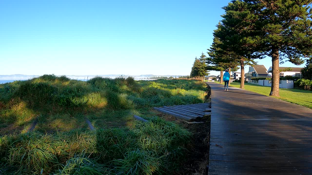 mujer caminando sobre una pista de madera junto a la playa