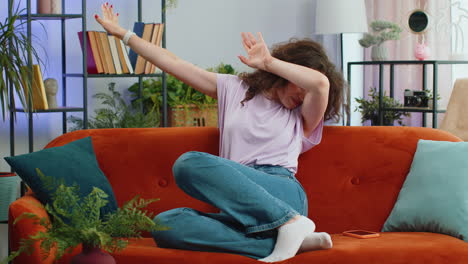 trendy cheerful woman dancing and moving to rhythm making dub dance winner gesture celebrate at home