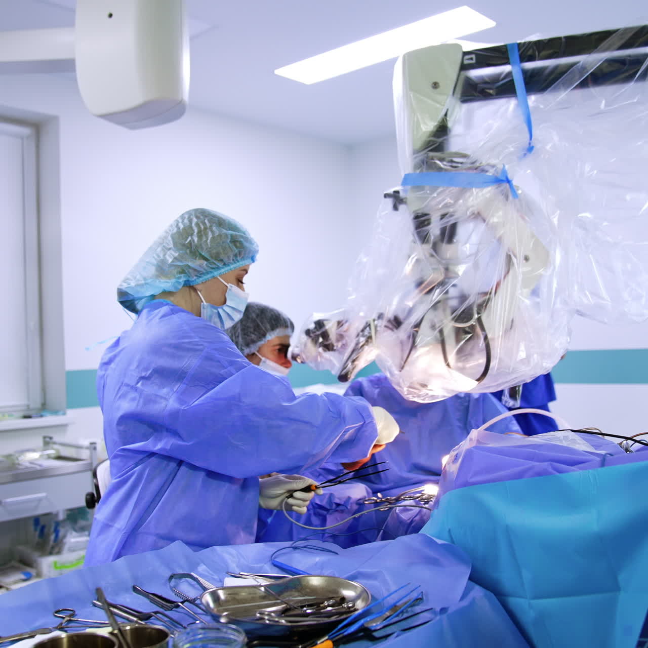 Female surgery assistant standing at the table with instruments. Medic passes the tools and disinfects ones received from the surgeon.