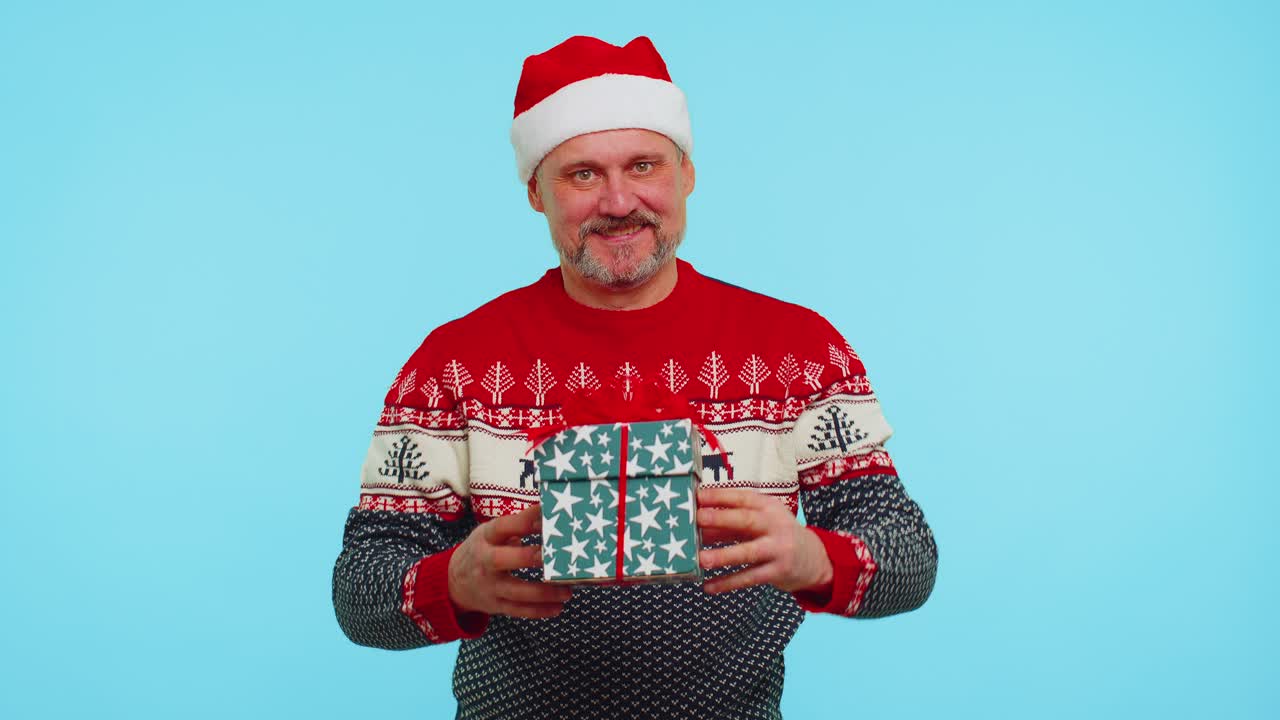 Funny man wears red new year sweater and hat presenting christmas gift box shopping sale holidays