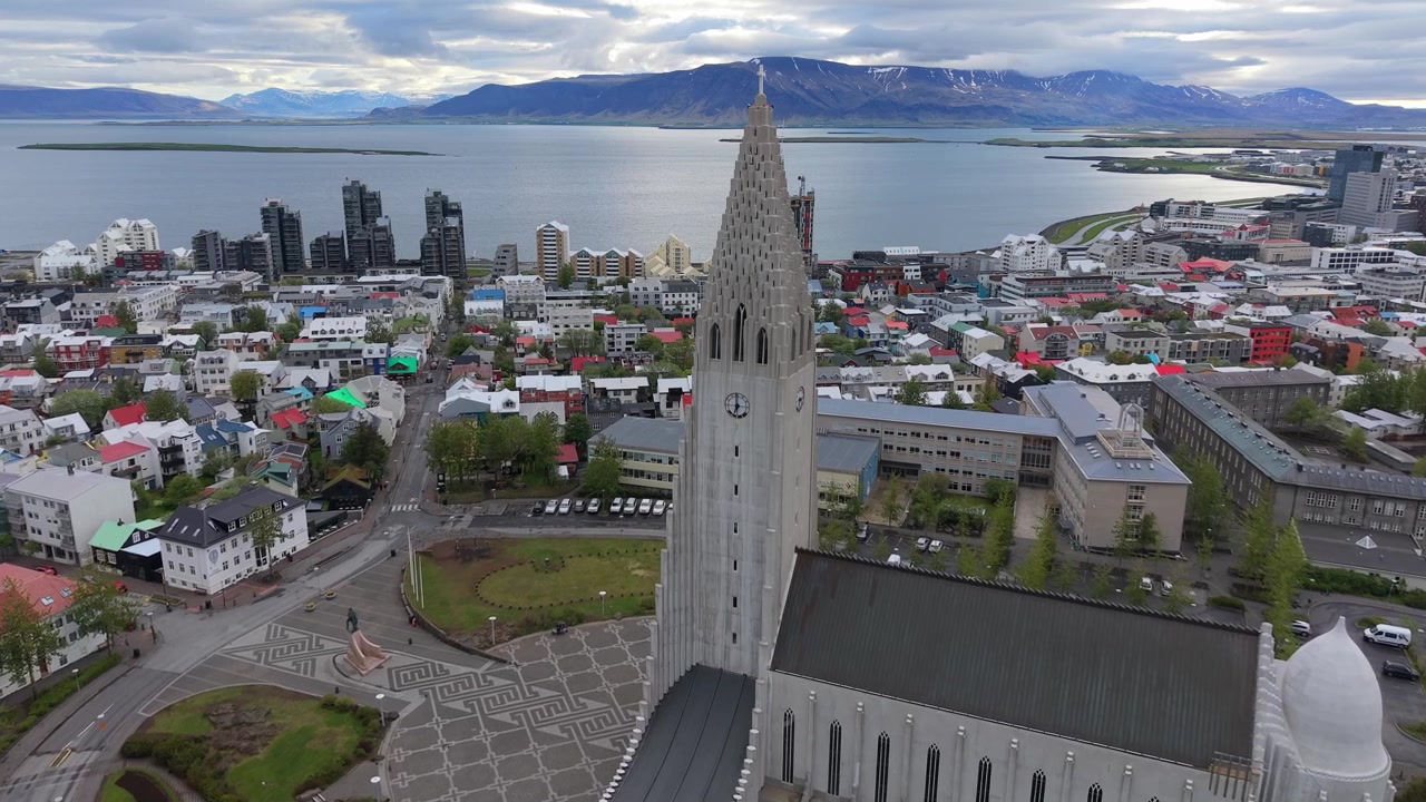 Rekaman udara dramatis yang mengelilingi gereja ikonik Hallgrimskirkja, menyingkap pemandangan kota panorama Reykjavik, Islandia yang menakjubkan