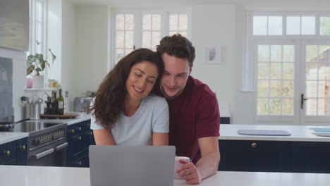 Loving-Transgender-Couple-At-Home-Together-Streaming-Movie-To-Laptop-On-Kitchen-Counter