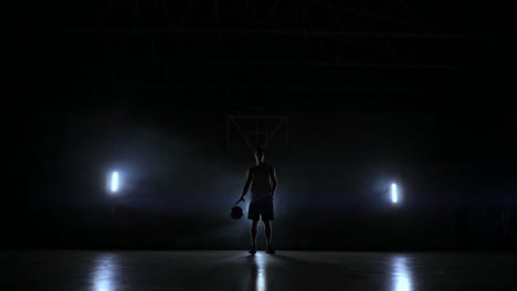 Dribbelnder-Basketballspieler-Im-Dunkeln-Auf-Dem-Basketballplatz-Mit-Hintergrundbeleuchtung-Im-Rauch.-Streetball-In-Zeitlupe