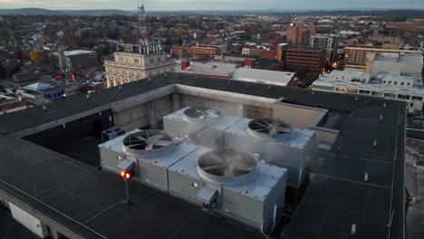 aerial orbit shot of rotating propeller of air conditioner on top of tower in lancaster city at sunset. pennsylvania, america