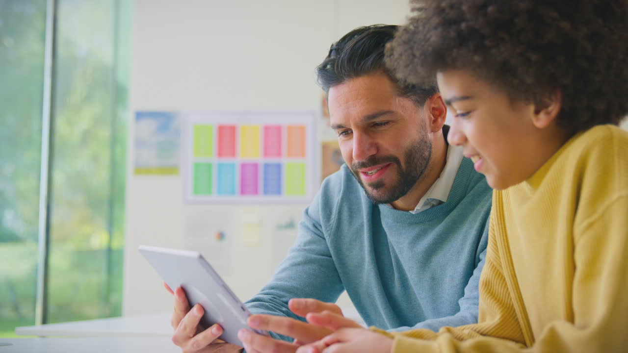 maestro y estudiante masculino en el aula de la escuela usando una tableta digital juntos
